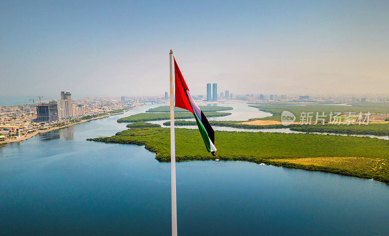 阿联酋国旗和Ras al Khaimah酋长国空中城市景观的标志性天际线上升在阿联酋北部的红树林和小溪